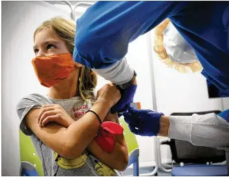  ?? MARSHALL GORBY / STAFF ?? Thea Schicel, age 6, looks at her mother while receiving her COVID-19 vaccine Monday at Dayton Children’s Hospital’s first clinic for kids 5 years and older.