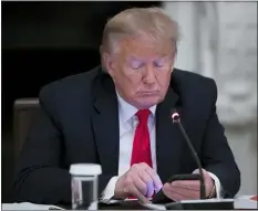  ?? ALEX BRANDON — THE ASSOCIATED PRESS ?? President Donald Trump looks at his phone during a roundtable with governors on the reopening of America’s small businesses, in the State Dining Room of the White House, Thursday, June 18, 2020, in Washington.