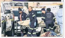  ?? ?? GRIEF: A woman weeps at the scene of a massacre in Johannesbu­rg that left at least 15 dead (inset). The violence was one of two mass shootings in South Africa between Saturday night and Sunday morning.