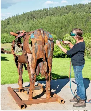  ??  ?? Wearing goggles for protection, Helen carries out some welding work on Elvis the bull in the fresh air next to her studio.