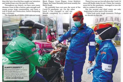  ??  ?? ALWAYS DISINFECT ... Malaysian Civil Defence Forces personnel offering food delivery riders hand sanitizers in Bukit Bintang, Kuala Lumpur. – ZAHID IZZANI/THESUN