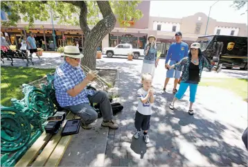  ?? LUIS SÁNCHEZ SATURNO/THE NEW MEXICAN ?? Angie Baca, right, of Santa Fe and 4-year old Rylee Roberts, center, of Miami dance on the Plaza on Wednesday to the trumpet-playing of busker Stan Engle of Oklahoma City.