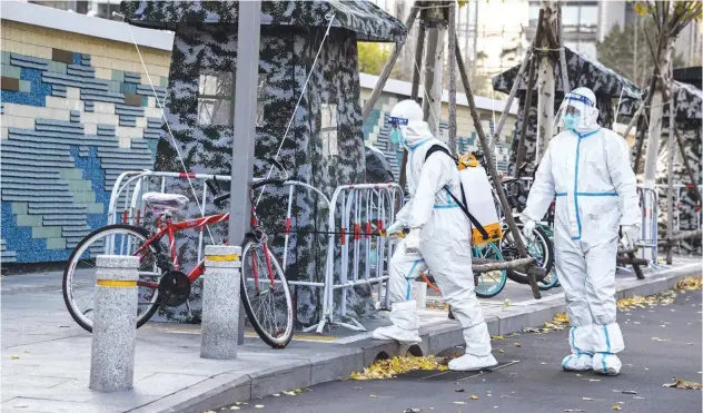  ?? Agence France-presse ?? ↑ Workers, wearing personal protective equipment, disinfect an area in Beijing on Saturday.