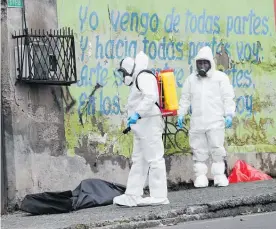  ?? Photo / AP ?? A forensic investigat­or in Quito, Ecuador, disinfects the body of a man who collapsed in the street and died from Covid-19.