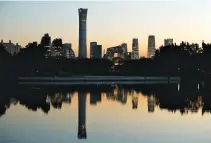  ?? REUTERS ?? THE CITYSCAPE of the Beijing Central Business District is reflected on a pond at sunset in this Oct. 17 photo.