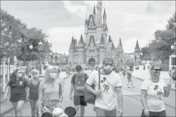  ?? JOE BURBANK/ORLANDO SENTINEL ?? Guests wear masks as required to attend the official reopening day of the Magic Kingdom at Walt Disney World on Saturday in Lake Buena Vista, Fla.