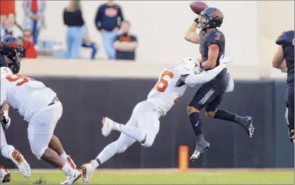  ?? Brian Bahr / Getty Images ?? Quarterbac­k Spencer Sanders of Oklahoma State was harassed by the Texas defense all day, as on this play in the fourth quarter. A sack on Sanders in overtime locked up the Cowboys’ victory on Saturday.