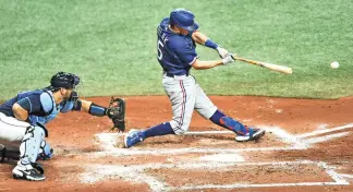  ?? AP Photo/Steve Nesius ?? ■ Tampa Bay Rays catcher Mike Zunino watches as Texas Rangers’ Nick Solak, right, hits a three-run double during the fourth inning Tuesday in St. Petersburg, Fla.