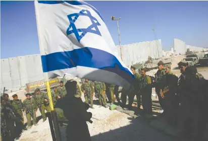  ?? (David Silverman/Reuters) ?? IDF SOLDIERS take part in a flag-lowering ceremony as they prepare to withdraw from Girit outpost, in the southern Gaza Strip, in 2005.