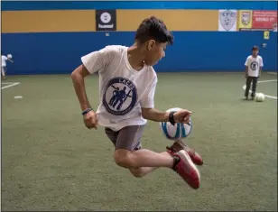  ??  ?? ABOVE: Quriesh Ahmad, 10, from Afghanista­n, practices a trick during a soccer camp for refugee children at Total Soccer Arena in Landover, Maryland.