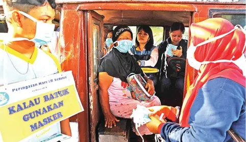  ?? DIPTA WAHYU/JAWA POS ?? HARI TB SEDUNIA: Sejumlah kader Aisyiyah Surabaya membagikan masker kepada penumpang dan sopir angkutan umum di Terminal Joyoboyo kemarin.