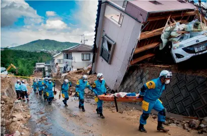  ?? AFP ?? Police arrive to clear debris scattered on a street in a flood-hit area in Kumano, Hiroshima prefecture, on Monday. —