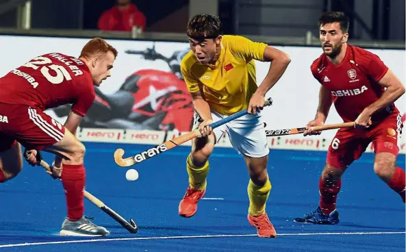  ??  ?? Going through: Su Wenlin of China dribbles past two England players during a Group B match in the hockey World Cup at the Kalinga Stadium in India on Friday. The match ended 2-2.