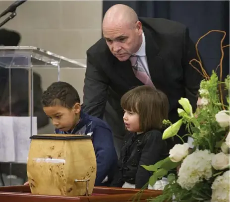  ?? BERNARD WEIL/TORONTO STAR ?? George Smitherman leads his two children, Michael, 5, and Kayla, 3, to see the urn onstage Friday during the public memorial for Christophe­r Peloso.