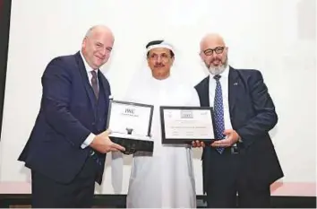  ?? Courtesy: The Swiss Business Council Abu Dhabi ?? Sultan Bin Saeed Al Mansouri, Minister of Economy, receiving the UAE Business Personalit­y of the Year 2017 from Luc Rocherau (left) and Jean-Marc Suter, in Abu Dhabi.