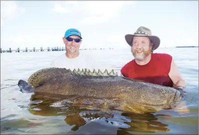  ?? COURTESY OF KEITH SUTTON ?? Fishing guide Ryan Rowan, left, helps Keith Sutton lift a 450-pound goliath grouper for a photograph. It’s the biggest fish Sutton has ever caught.
