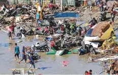  ?? AP ?? People survey outside a shopping mall that was badly damaged following earthquake­s and a tsunami in Palu.