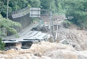  ??  ?? A road is destroyed following torrential rain near the Kuma river in Ashikita, Kumamoto prefecture.