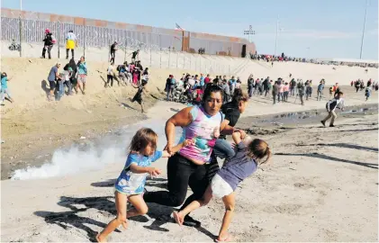  ?? Picture: Reuters ?? US ON THE OFFENSIVE: Maria Meza, centre, and her twins run from tear gas at the United States-Mexico border. From Honduras, they’re part of a caravan from Central America trying to reach the US.