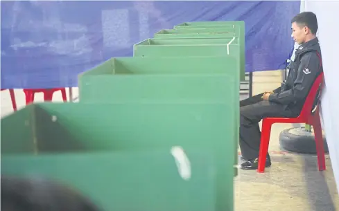  ?? BANGKOK POST PHOTO ?? A police officer guards a polling booth for the 2016 charter referendum. The long-awaited general election now looks likely to be delayed again.