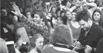  ?? PHOTO BY GARETT FISBECK, TULSA WORLD ?? The Swon Brothers, from left, Colton and Zach, are greeted by fans as they get off a bus at the Civic Center in Muskogee.