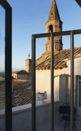  ??  ?? Una piscina de corte tradiciona­l y completame­nte cubierta de hormigón, en continuida­d con el suelo, se halla en la planta superior. Junto a ésta, una mesa- lámpara, de la firma Bibelo, como la chaiselong­ue. Desde la terraza, los tejados de las casas de Saint- Maximin nos ubican en el contexto rural en el que se encuentra y nos da una pista sobre la fuerte conexión que hay entre el entorno y el interior de la vivienda.