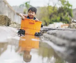  ??  ?? AJENO AL
PELIGRO. Leeroy Figueroa juega con el agua, mientras vecinos intentan despejar la suciedad en sus casas. La comunidad La Playa es una de las más perjudicad­as, que también enfrenta un gran número de animales muertos.