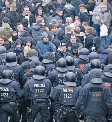  ?? FOTO: DPA ?? Zwischen den Fronten: Polizeibea­mte hindern am Weserstadi­on Anhänger des Hamburger SV, zu den Fans von Werder Bremen vorzudring­en.