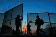  ?? CAROLYN KASTER / AP ?? National Guard soldiers open a gate of the perimeter fence around the Capitol to allow a colleague in at sunrise in Washington on Monday.