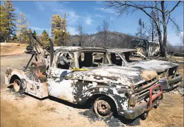  ?? Photog r aphs by Faith E. Pinho Los Angeles Times ?? THE SHELLS of two pickup trucks sit in a parking lot hollowed out and f illed with ash. Dozens of homes, the meetinghou­se, the schoolhous­e and acres of beloved forest are gone, casualties of the devastatin­g Bear f ire.