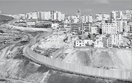  ?? Thomas Coex AFP/Getty Images ?? A WALL separates East Jerusalem, left, and the West Bank village of Anata. Terrorist attacks in Isarel have ebbed since constructi­on of the wall began in 2000, but the decline has multiple causes. The barrier also has inflamed tension and resentment...