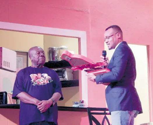  ?? ?? Oliver Samuels (left) receiving his Red Stripe Living Legend award from Brand Manager Nathan Nelms at the Little Theatre on Friday night.