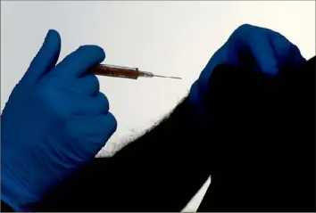  ?? Frank Augstein/Associated Press ?? Dr. Anil Mehta administer­s the AstraZenec­a vaccine to a patient on Feb. 5 at the Wellcome Centre in Ilford, east London.