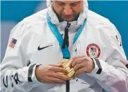  ?? THE ASSOCIATED PRESS ?? U.S. men’s curling skip John Shuster examines his medal after the Americans beat favored Sweden 10-7 in the gold final Saturday in Gangneung, South Korea. His team went from the brink of eliminatio­n in pool play to first place.