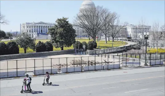  ?? Patrick Semansky The Associated Press ?? People ride scooters past an inner perimeter of security fencing Sunday on Capitol Hill in Washington.