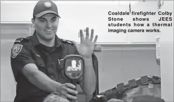  ??  ?? Coaldale firefighte­r Colby Stone shows JEES students how a thermal imaging camera works.