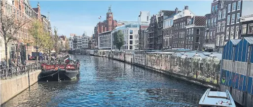  ?? BRANDIE WEIKLE FOR THE TORONTO STAR ?? A boat manoeuvres along a canal lined with 17th-century buildings in central Amsterdam.