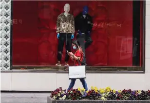  ?? ANDREW FRANCIS WALLACE TORONTO STAR ?? A woman walks past a Louis Vuitton window in Toronto on Tuesday. Premier Doug Ford has given retail stores outside of malls the green light to open this week.