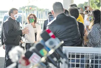  ??  ?? El presidente de Brasil, Jair Bolsonaro (izq.), dialoga con los periodista­s y ciudadanos en las afueras del Palacio da Alvorada, en el marco de la crisis de la pandemia del covid-19. (AFP)
