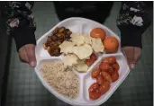  ?? WONG MAYE-E — THE ASSOCIATED PRESS ?? A 7th grader carries her plate which consists of three bean chili, rice, mandarins and cherry tomatoes and baked chips during her lunch break at a local public school, in the Brooklyn borough of New York.