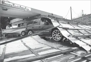  ?? ELIZABETH CONLEY/ASSOCIATED PRESS ?? Parts of a roof sit on top of a car Tuesday following Hurricane Nicholas in Bay City, Texas. According to the owner of the business, he wasn’t sure where the roof came from.