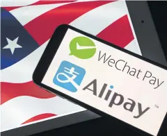  ?? BLOOMBERG ?? The logos of Tencent Holdings Ltd’s WeChat Pay and Ant Group’s Alipay are arranged on a smartphone in front of an American flag in Hong Kong.