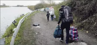  ?? Rafael Yaghobzade­h / Associated Press ?? Migrants walk near a makeshift camp set up along the river in Loon Plage, near Grande-Synthe, northern France, on Friday.