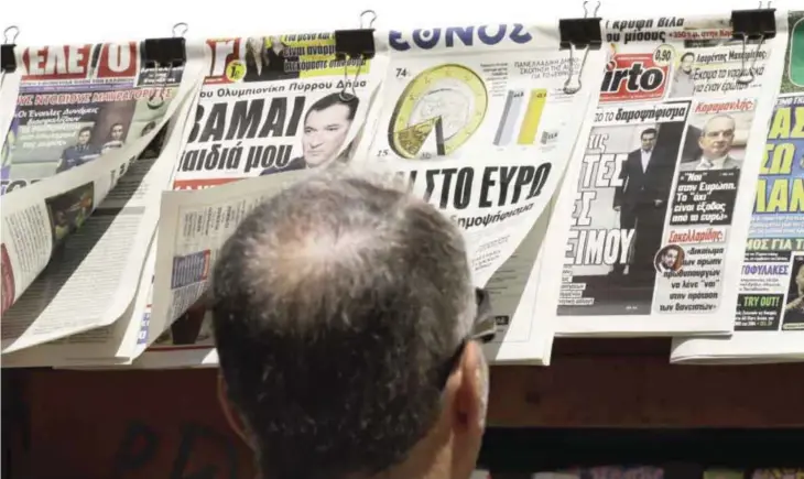  ?? — AP ?? ATHENS: A man reads the front pages of the Greek newspapers in Athens yesterday. The brief but intense campaign in Greece’s critical bailout referendum endedyeste­rday, with simultaneo­us rallies in Athens supporting “yes” and “no” answers to a murky...