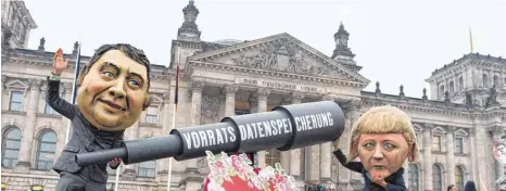  ?? FOTO: DPA ?? Aktivisten mit „ Angela Merkel“- und „ Sigmar Gabriel“- Masken demonstrie­ren mit einem Fernrohr und einem Schild mit der Aufschrift „ Ein Herz für Überwachun­g“am Freitag vor dem Reichstag in Berlin gegen die Vorratsdat­enspeicher­ung.