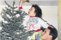  ?? CONTRIBUTE­D ?? Ruby Patey’s daughter, Rana, pins the star atop their tree. Patey now lives in Grand Falls-Windsor, N.L., but grew up in St. Jacques, where her Christmas tree would magically appear on Christmas morning.