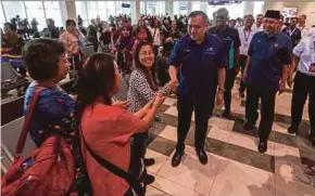  ?? PIC BY NIK ABDULLAH NIK OMAR ?? Transport Minister Anthony Loke greeting passengers at Sultan Ismail Petra Airport ahead of the launch of Phase 1 of the airport’s extension project, in Kota Baru yesterday.