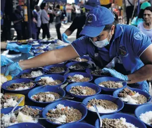  ?? PHOTO: REUTERS ?? Relief effort . . . A volunteer serves lunch at a community kitchen set up by USAID and World Food Programme in Cucuta, Colombia, on the border with Venezuela, where food and medical aid is being stored in warehouses, while the border remains blocked to its passage.