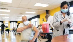  ?? JOSE M OSORIO/CHICAGO TRIBUNE ?? Austin Banton, 77, rolls his sleeve up for his first dose of the Moderna COVID-19 vaccine at the Mahalia Jackson Apartments in Chicago on Thursday.