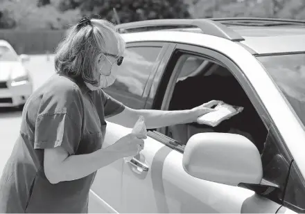  ??  ?? Brenda Hoopers hands out a pack of masks during a free drive-thru mask distributi­on July 8 at the Chabad Community Center for Jewish Life and Learning. [SARAH PHIPPS/ THE OKLAHOMAN]